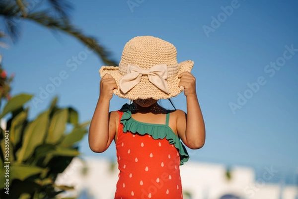 Fototapeta Funny little girl relaxing on summer vacation. The child has fun on the beach. Cute baby in a colorful swimsuit and sunglasses is resting.