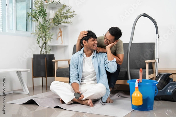 Obraz Intimate cleaning moment. Two friends share laughter and affection while vacuuming.