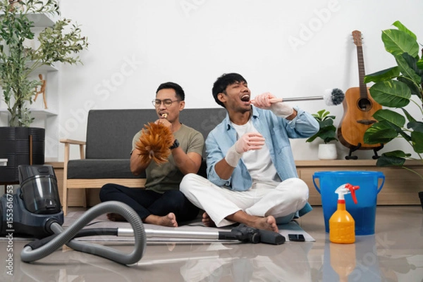 Obraz Fun Cleaning Session with Friends. Two young men enjoying music while cleaning their home.