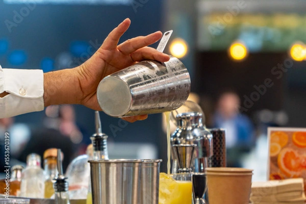 Fototapeta Bartender mixing orange cocktail with ice on a summer festival