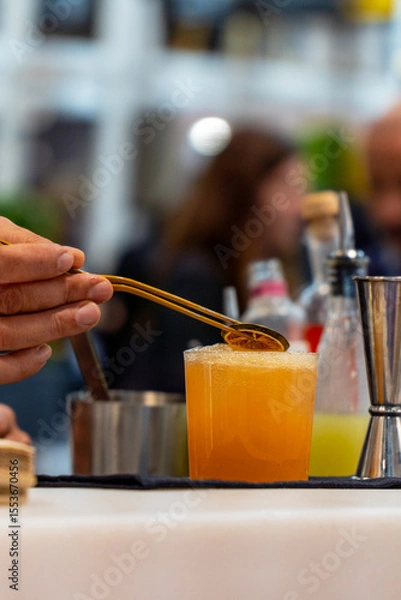 Fototapeta Bartender carefully placing orange slice on refreshing cocktail