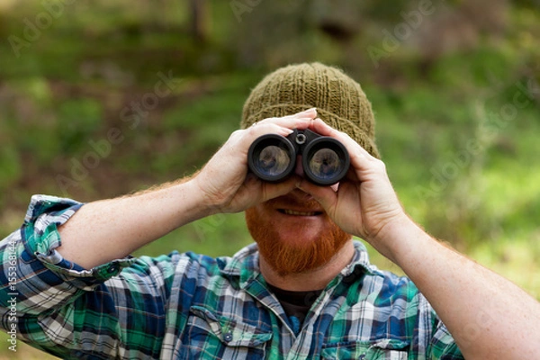 Fototapeta Young Man using binoculars