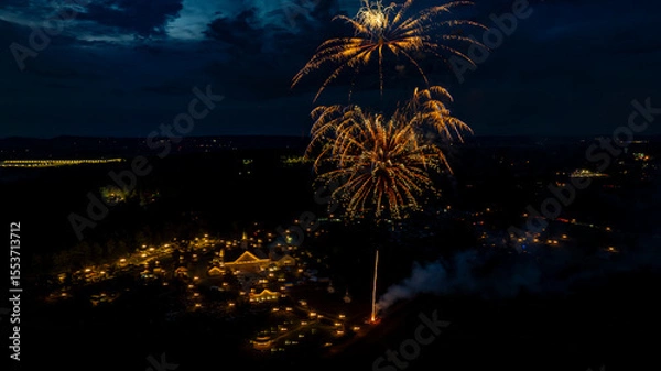Fototapeta Colorful fireworks burst in the night sky above a lively festival. Bright lights illuminate the gathering below, where people enjoy festivities. The atmosphere is vibrant and filled with excitement.