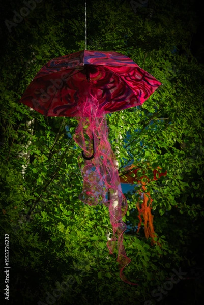 Fototapeta Umbrella suspended on green leaf tree with sunset color