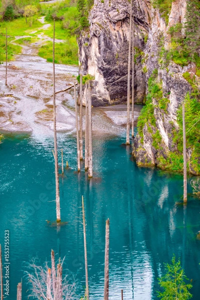 Obraz Sunken forest of Lake Kaindy in Kazakhstan. Beautiful mountain natural landscape. A blue lake with tree trunks sticking out of it. Panoramic view of the reserve.