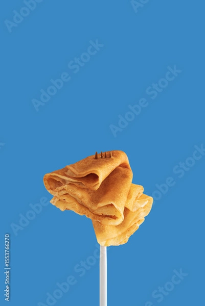 Obraz Golden pancakes on a fork against a vibrant blue background.