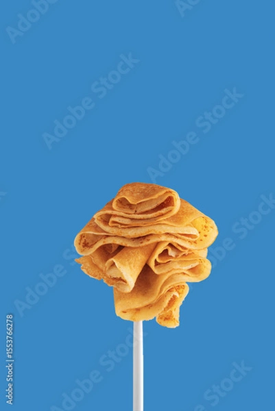 Obraz Golden pancakes on a fork against a vibrant blue background.