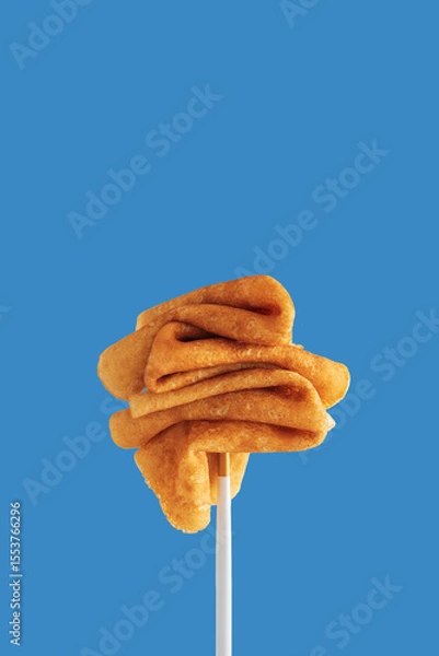 Obraz Golden pancakes on a fork against a vibrant blue background.