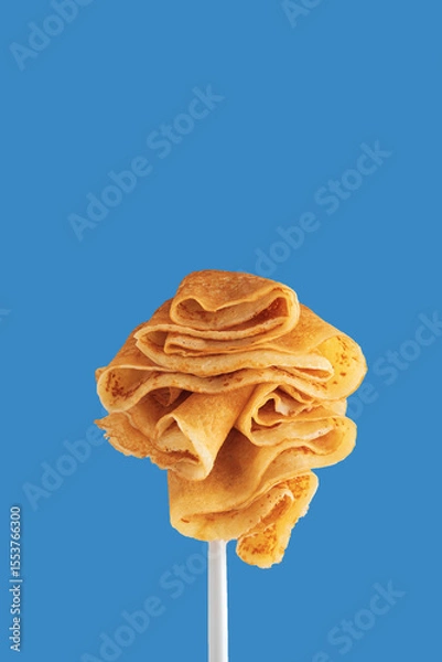 Obraz Golden pancakes on a fork against a vibrant blue background.