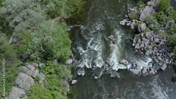 Fototapeta Aerial view of a turbulent stream in the mountains. Gusts of wind swaying tree branches.