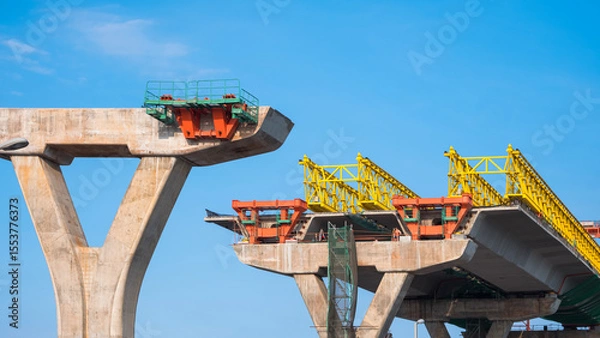 Fototapeta Metal launching gantry on foundation of elevated expressway structure against blue sky background, Perspective side view