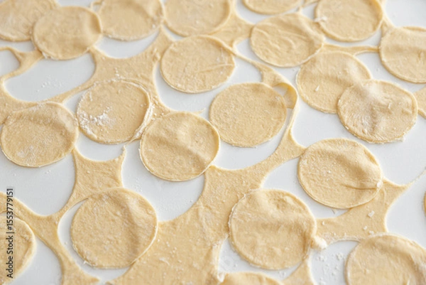 Obraz Raw homemade dumpling dough circles on a white surface.