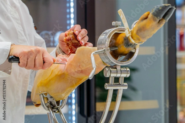 Fototapeta Spanish iberian ham cutting on a restaurant by a professional waiter with expertise in tapas