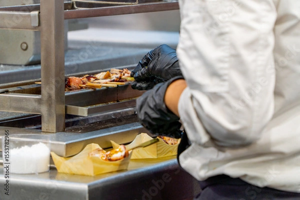 Fototapeta Chef plating grilled vegan meat appetizers with black gloves on sustainable trays