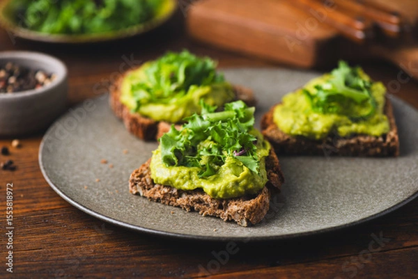 Fototapeta Healthy delicious vegan rye bread toast with mashed avocado and kale