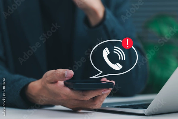 Obraz Phone Scam Alert and Warning Notification Concept. A person holding smartphone displaying call icon with alert symbol, representing scam call warnings, fraud awareness, digital communication threats,