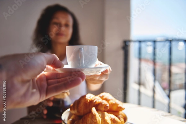 Fototapeta Warm summer morning featuring freshly brewed coffee, buttery croissants, and serene joy shared with a companion on a sunny balcony with a pleasant, scenic background.