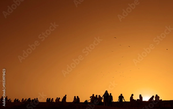 Obraz Silhouette back rear view of group happy people friends team sitting together on sunset sky evening time for business success and teamwork concept in company. Kalemegdan fortress. sunrays bokeh