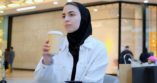 Obraz Young woman engaging with smartphone while enjoying coffee in trendy cafe, embodying modern digital connectivity and leisurely urban lifestyle during focused moment of communication