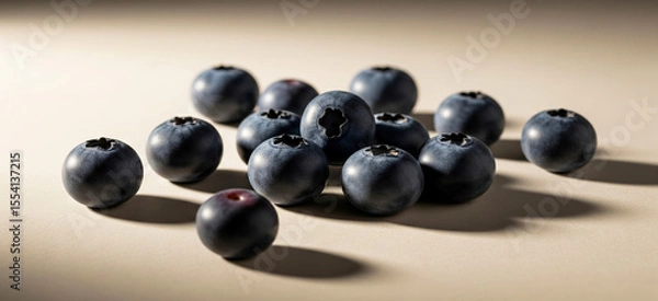 Fototapeta A small pile of blueberries sits on a plain light brown surface.