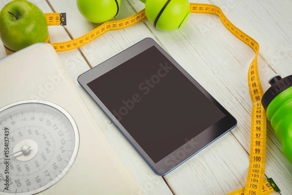 Fototapeta High angle view of digital tablet and tape measure on table