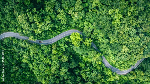Obraz Aerial view of a road in the middle of the forest , road curve construction up to mountain