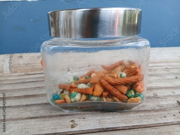 Fototapeta A mix of snacks during Eid such as Bogor peanuts, which taste savory and salty, in a jar on a bamboo chair
