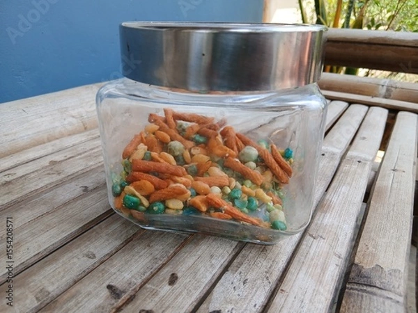 Fototapeta A mix of snacks during Eid such as Bogor peanuts, which taste savory and salty, in a jar on a bamboo chair