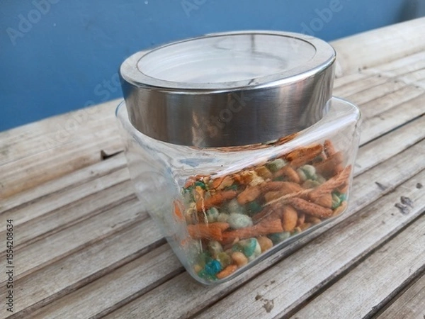 Fototapeta A mix of snacks during Eid such as Bogor peanuts, which taste savory and salty, in a jar on a bamboo chair