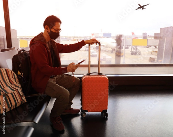 Fototapeta Travel trip with asian young man and backpack as looking the airplane in the hall room with sunlight in the airport terminal