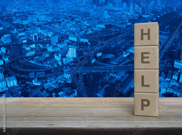 Fototapeta HELP letter on wood block cubes on wooden table over modern city tower, street, expressway and skyscraper, Business customer service and support concept