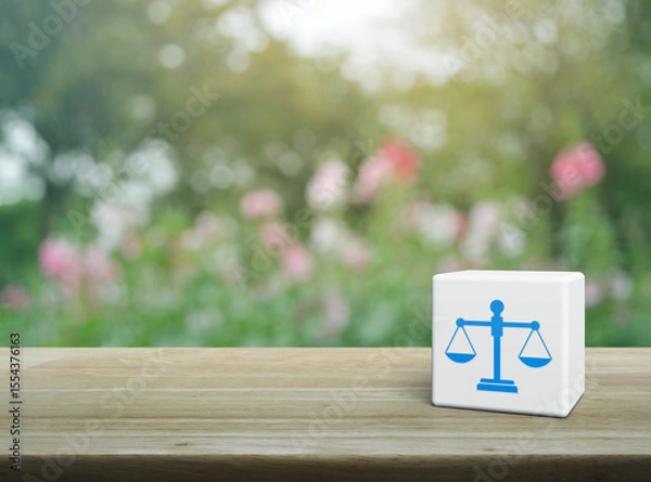 Fototapeta Law flat icon on white block cube on wooden table over blur pink flower and tree in garden, Business legal service concept