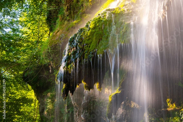 Fototapeta The Urach waterfall on the edge of the Swabian Alb is a high waterfall with tufa deposits. Detail with long exposure effect after heavy rain in summer. Popular tourist attraction in a natural reserve.