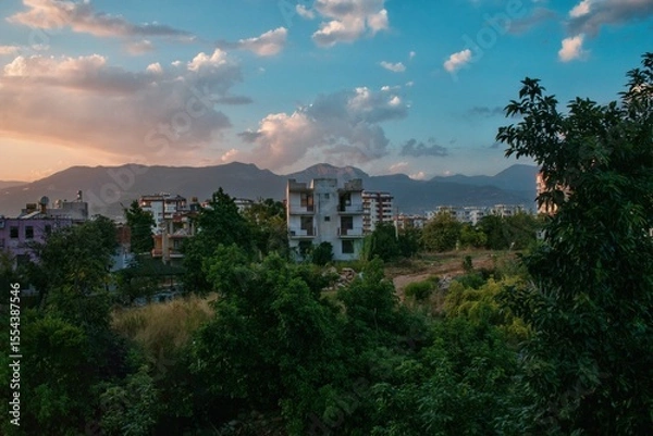 Fototapeta Cloudy sky over old village houses in Turkey with tree leaves in the foreground