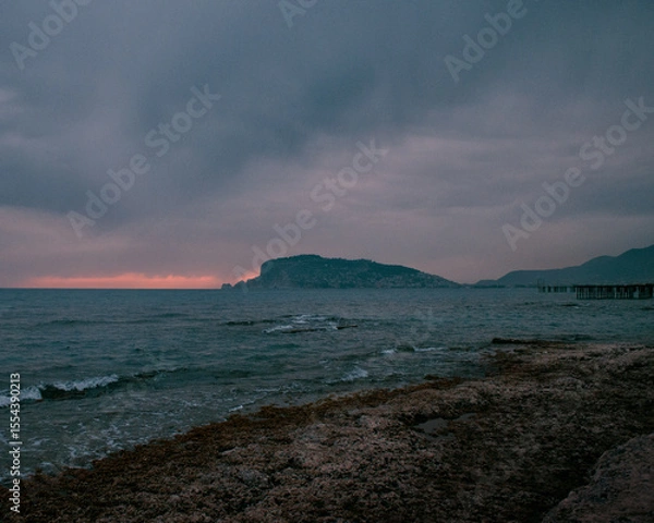 Fototapeta Dark sea with whitecaps after sunset and dramatic clouds