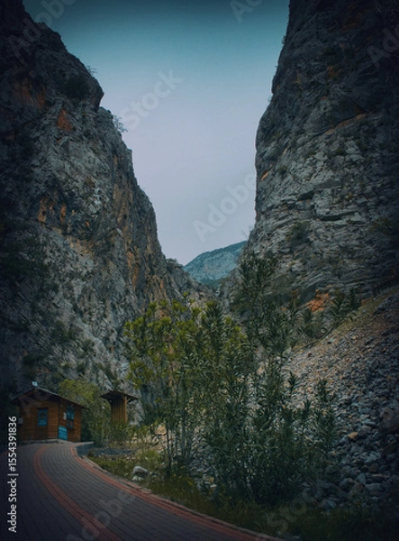 Fototapeta Winding mountain road leading to scenic gorge in sunlight