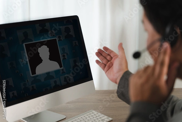 Obraz Call center person participating in virtual meeting on computer, wearing headset and gesturing with their hand, in professional setting