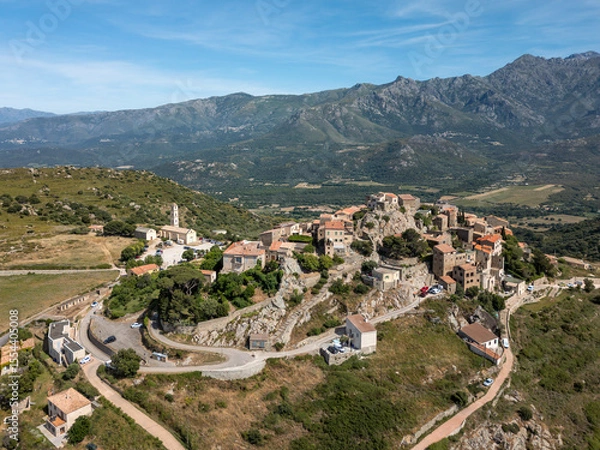 Fototapeta Aerial view of the medieval hilltop village of Sant’Antonino on the Mediterranean island of Corsica with mountains in the distance