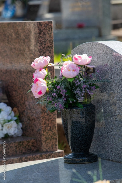 Fototapeta Le fleurissement d’une tombe avec un bouquet de fleurs rose. Cela permet de rendre hommage au défunt et de témoigner son attachement et le respect envers cet être cher.