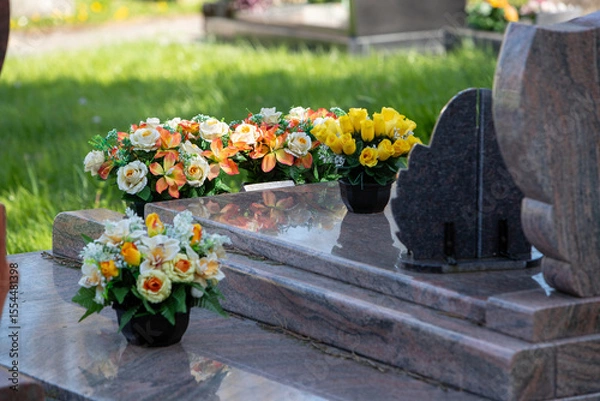 Fototapeta Le fleurissement d’une tombe avec un bouquet de fleurs orange. Cela permet de rendre hommage au défunt et de témoigner son attachement et le respect envers cet être cher. 
