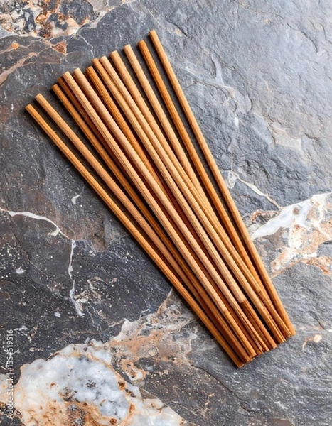 Fototapeta Artistic arrangement of bamboo incense sticks on a textured granite surface with earthy tones
