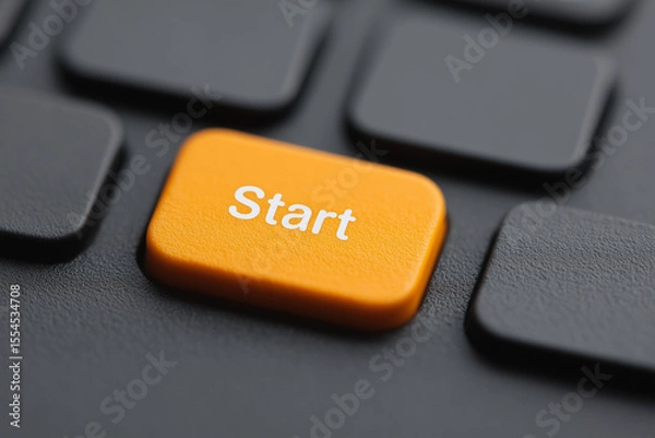 Fototapeta Orange start button on keyboard symbolizing power, initiation, and system boot—keycap closeup representing launch, activation, and interactive computing control