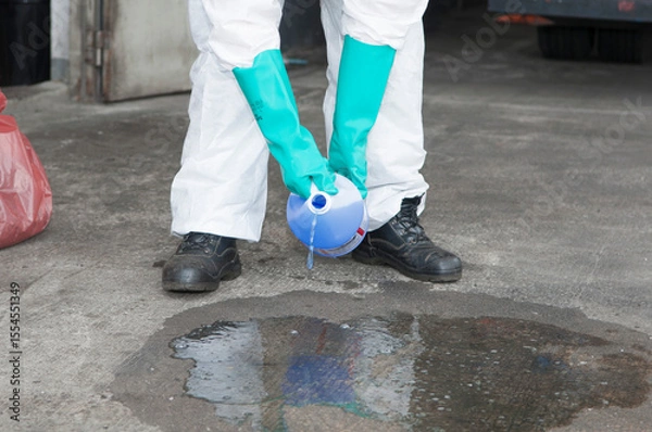 Obraz Hazmat Worker Collecting Spilled Liquid in Blue Container