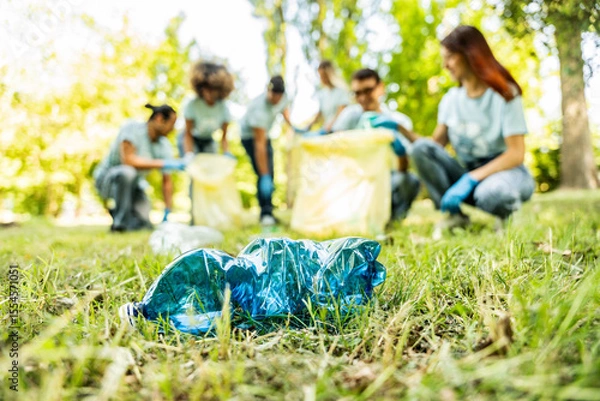 Fototapeta Group of volunteer cleaning picking up plastic litter in the park - Diverse group of people collect trash in the forest - Environmental protection, non profits organization and save the planet concept