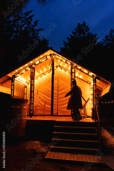 Obraz Glamping from tent houses in the forest in the dark. silhouette of a woman
