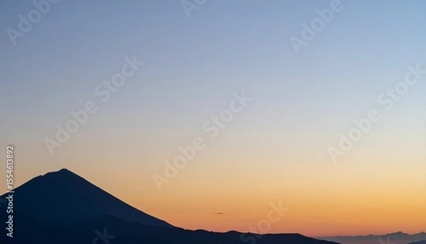 Obraz 火山の山影が静かに佇み、右側には柔らかな夕焼け色が広がるマットな空が大きく開け、滑らかなグラデーションで穏やかな時間を描く風景写真