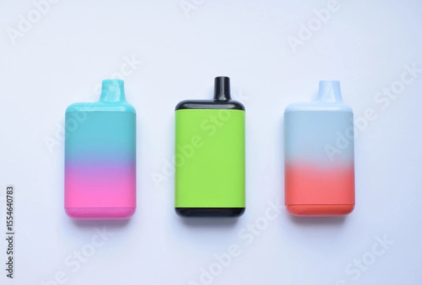 Fototapeta Several multi-colored electronic cigarettes lie on a light table.