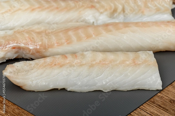 Obraz Fresh fish, cod loin on a chopping board close-up