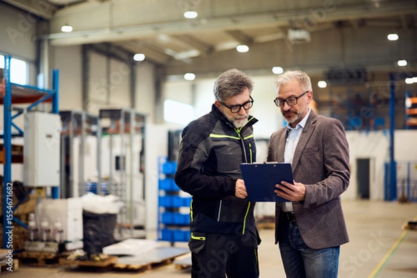Fototapeta Two Professionals Reviewing a Document Together Inside a Modern Industrial Facility