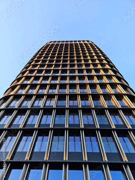 Fototapeta A tall building with many windows and a blue sky in the background. The building is very tall and has a lot of windows